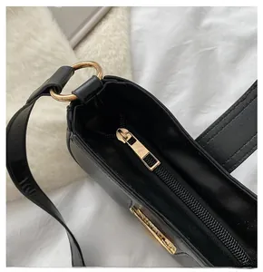 Close-up of smooth gold-tone zipper and textured black leather surface of the bag
