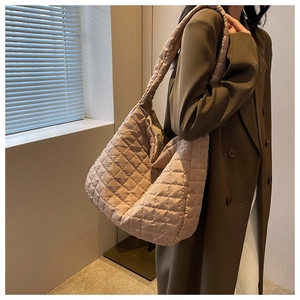 Detailed side view of beige quilted tote bag showing large capacity and puffy texture