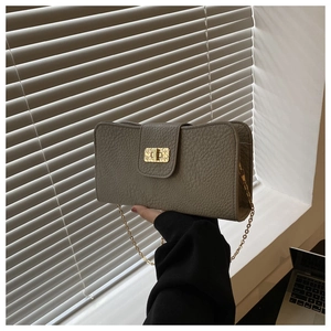 Vue détaillée du sac en cuir grainé avec fermoir rotatif doré et bandoulière en chaîne