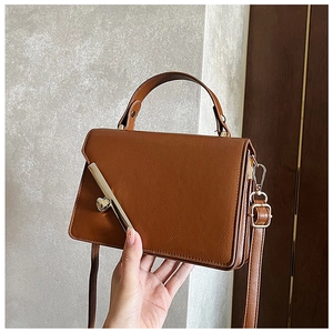 Close-up of brown PU leather bag featuring a diagonal metal bar and heart-shaped lock
