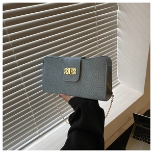 Détail du sac à main bleu clair en cuir grainé avec chaîne dorée et fermoir pivotant