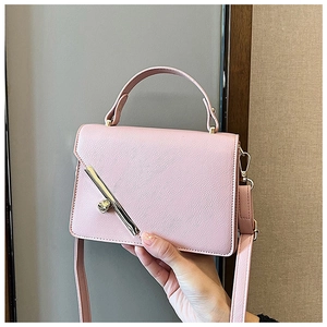 Detail of pink faux leather square bag with litchi texture and gold metal hardware