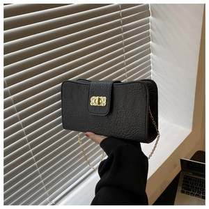 Détail du sac bandoulière en cuir grainé noir avec chaîne dorée et fermoir métallique