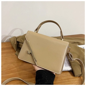 Close-up of beige textured leather handbag featuring golden metal clasp and handle