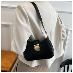 Detail of a black faux leather underarm bag with golden metallic clasp and slim strap
