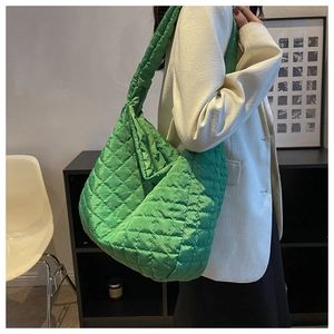 Detailed view of neon green quilted tote bag with diamond stitching on a female model