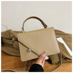 Detail of light beige leather crossbody bag with elegant gold metal lever lock closure