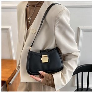 Model wearing black leather underarm bag with gold buckle to show size and fit