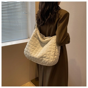 Rear view of a model wearing a large white quilted tote bag with a soft puffy texture