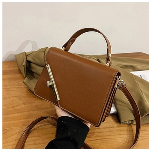 Detail view of brown retro handbag with vintage metallic bar closure and leather texture