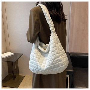 Detail of a large white quilted shoulder bag with glossy finish and rhombus stitching