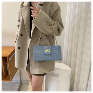 Sac bleu à texture litchi avec bandoulière chaîne dorée porté par un mannequin