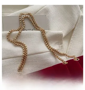 Close-up of golden hardware chain on red velvet quilted crossbody bag for women