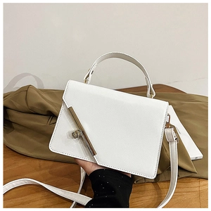 Detail of white square bag with lychee grain texture and gold metal hardware