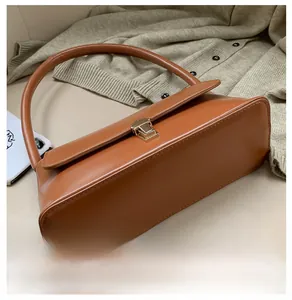 Close-up of caramel leather handbag base with gold buckle and neat stitching details