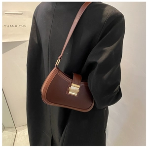 Close-up of brown leather crescent bag with gold buckle and black blazer on model