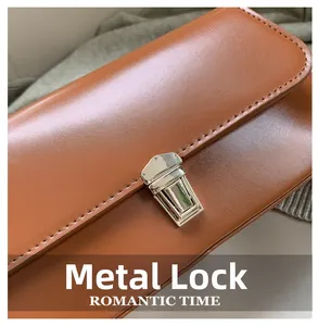 Detail of silver rectangular metal clasp on caramel brown leather baguette shoulder bag