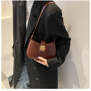 Close-up of a brown half-moon shoulder bag with a gold rectangular metal clasp buckle