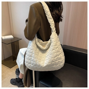Detail view of large white quilted tote bag with soft padded texture and wide shoulder strap