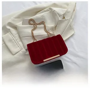 Dark red velvet chain bag featuring vertical quilting and gold metal trim details