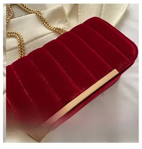 Detail of burgundy velvet handbag showing vertical quilting and golden chain strap