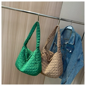 Detail of quilted tote bags in green and beige colors hanging with a denim jacket