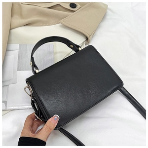Detail of black pebbled leather crossbody bag with elegant gold hardware and fixed handle