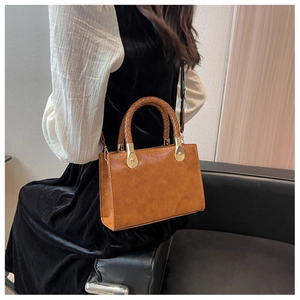 Dettaglio della borsa in pelle PU marrone con manico intrecciato e fibbie dorate