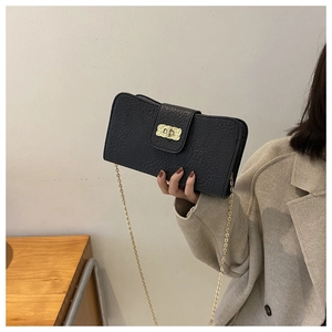 Détail d'un sac bandoulière noir à motif litchi avec chaîne et fermoir dorés élégants