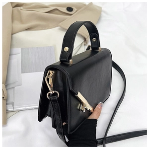 Detail view of black pebble leather crossbody bag with gold hardware and turn-lock