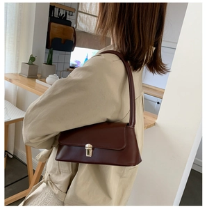 Dark brown retro baguette shoulder bag with gold clasp shown on model in indoor setting