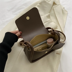 Brown leather crossbody bag showing internal capacity with mobile phone and cosmetics