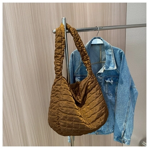 Detail of the brown quilted nylon shoulder bag with shiny padded texture and wide strap