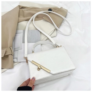 Detail of white square crossbody bag with gold rectangular twist lock on fabric