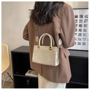 Dettaglio di elegante borsa a mano con tracolla intrecciata e finiture in oro lucido