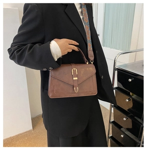 Dettaglio della borsa a tracolla vintage marrone con fibbia dorata e tracolla etnica