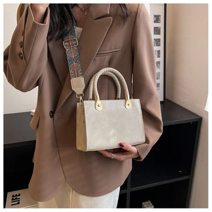 Dettaglio borsa beige con manico intrecciato e tracolla larga con motivi etnici colorati
