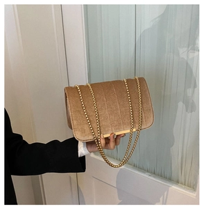 Detail of khaki velvet shoulder bag featuring gold chain strap and vertical quilting texture