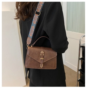Dettaglio borsa vintage marrone con ampia tracolla in tessuto con motivi bohémien