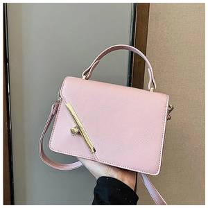 Detail of pink faux leather handbag showing golden bar twist-lock and lychee texture