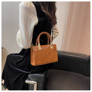 Dettaglio della borsa vintage marrone con manico intrecciato e fibbie dorate