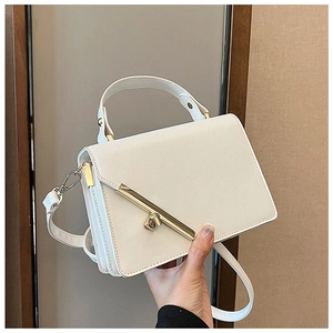 Detail of white textured leather handbag with gold metal bar trim and twist-lock clasp