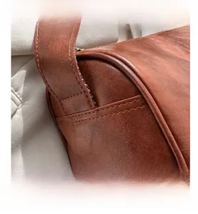 Nahaufnahme der braunen Ledertasche mit feinen Nähten und breitem Schultergurt-Detail