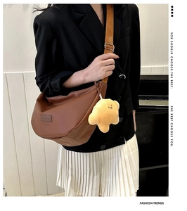 Detail of soft dark brown crescent bag with FASHION logo and yellow plush charm