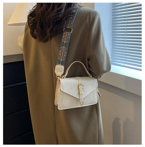 Dettaglio borsa in pelle beige con fibbia dorata e tracolla etnica in tessuto