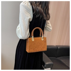 Borsa a tracolla quadrata marrone con manico intrecciato e dettagli dorati sulla modella