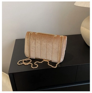 Close-up of champagne velvet quilted texture and gold chain on the shoulder bag
