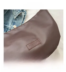 Macro detail of dark brown leather shoulder bag with FASHION stitched leather label