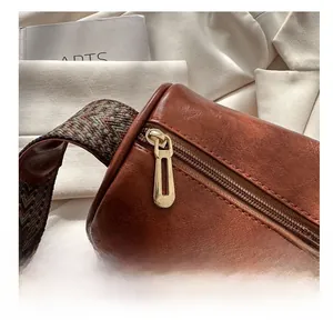 Detail eines goldenen Reißverschlusses und gewebten Riemens an einer braunen Tasche