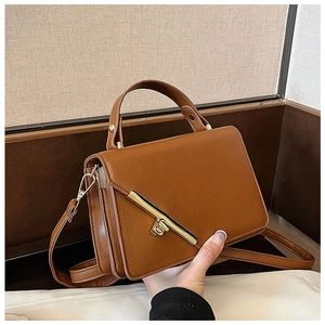 Detail of caramel faux leather handbag with golden lock and detachable shoulder strap